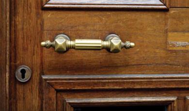 Image of a close-up of a wooden door with a brass door handle and a keyhole