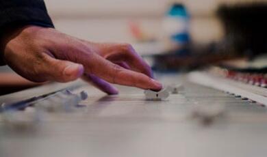 Hand adjusting sound level on mixing desk