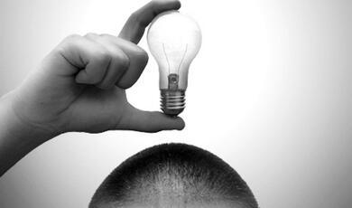 a black and white image of a person holding a lightbulb above their head