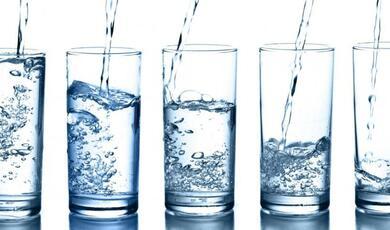 a line of 5 drinking glasses with different levels of water being poured into them