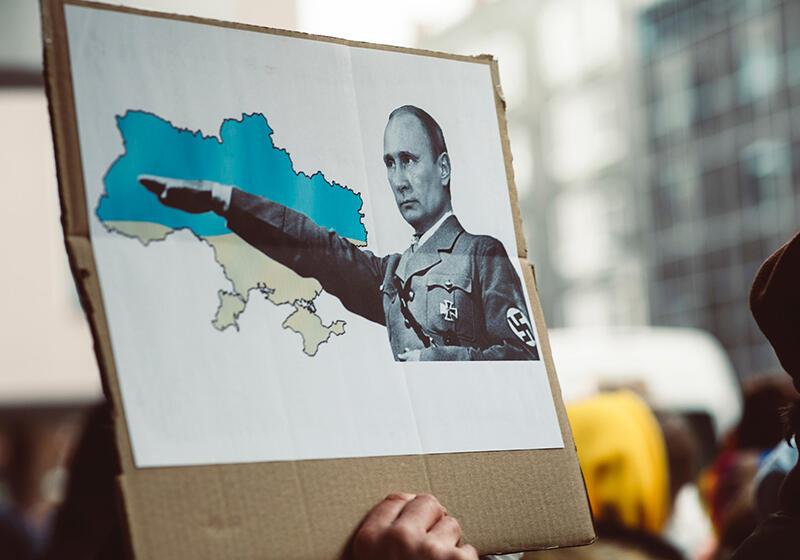 Putin dressed as a Nazi with an image of Ukraine on a piece of cardboard