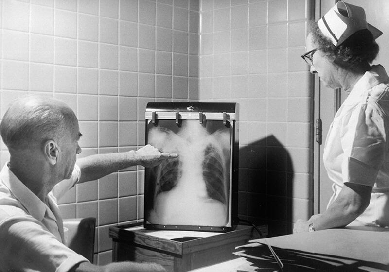 a black and white photograph of a nurse and doctor examining an x-ray