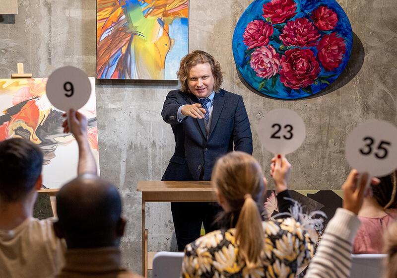 an auction scene with people holding up the numbers 9, 23 and 35