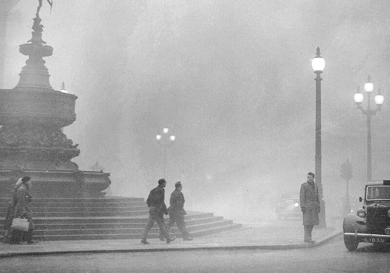 a black and white photograph of people in the London smog