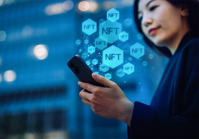 a lady looking at smartphone with NFT graphics rising from it