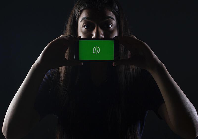 Woman in near darkness holding mobile phone up to the camera