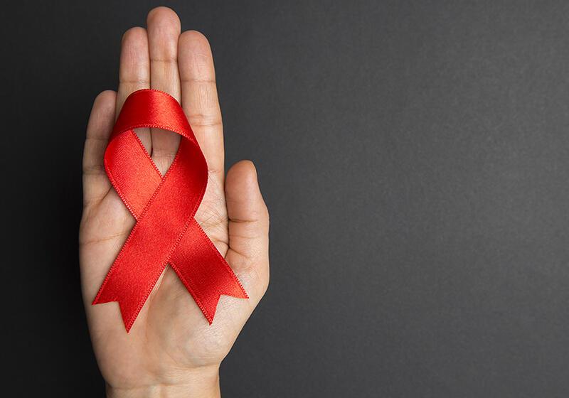 Hand holding red AIDS awareness ribbon