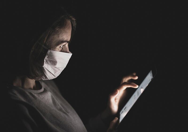 a woman wearing a mask looking at her smartphone in the dark