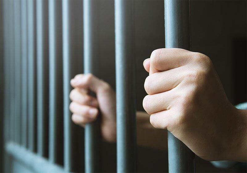 a pair of hands gripping prison cell bars