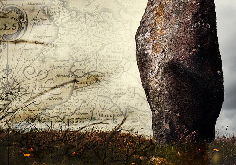 an old map of Wales next to an ancient stone