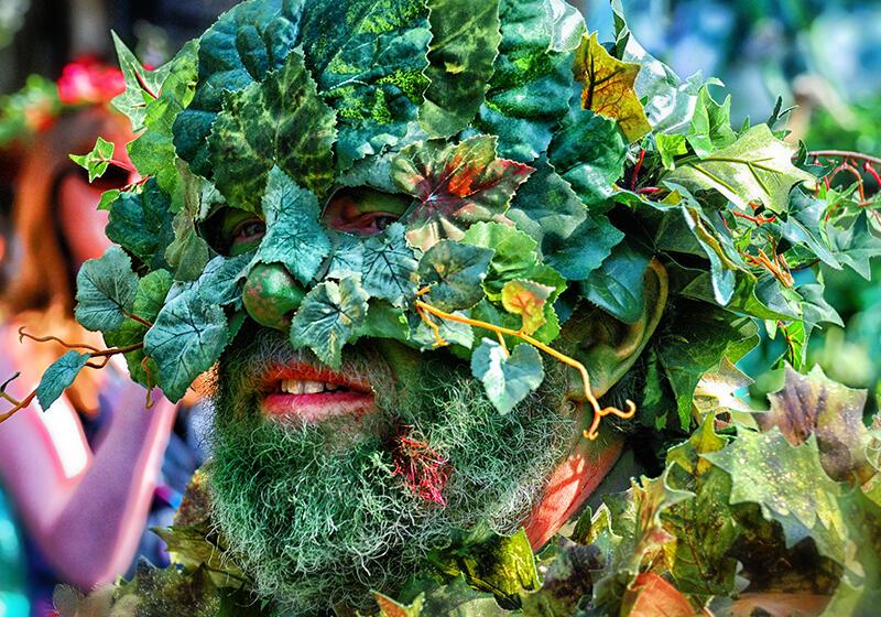 a man's face wearing a mask made of plants