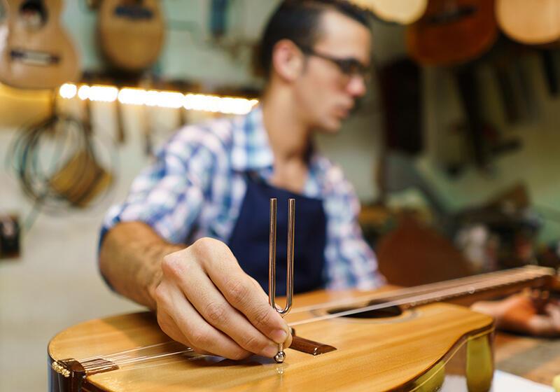 Man using tuning fork on guitar