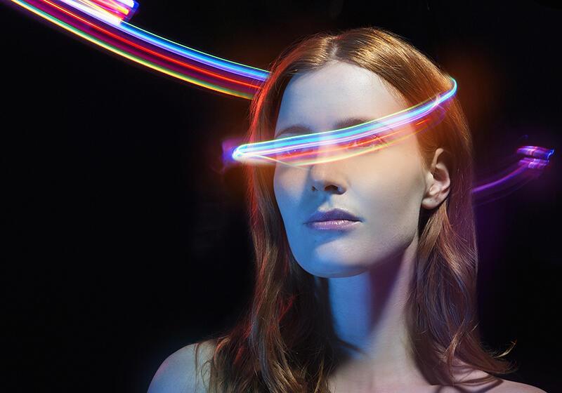 a woman with colourful beams swirling around her head