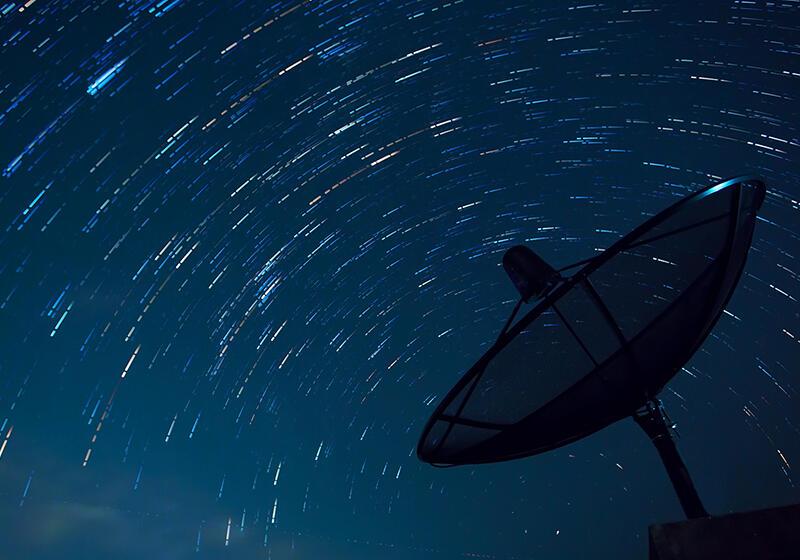 a satellite dish in the night sky full of stars