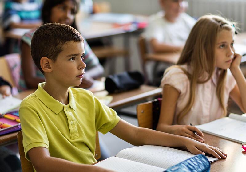 a boy and a girl sitting at desks in a classroom