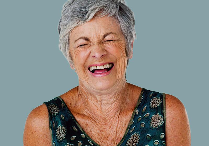 Close-up of a senior woman with short grey hair laughing joyfully