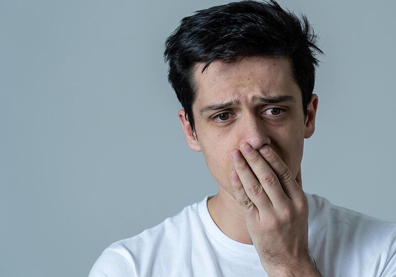 A man with a worried expression covers his mouth with his hand