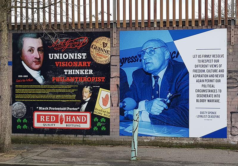Two side-by-side murals: one celebrating a historical unionist figure with bold text and symbols, and the other showing an older man speaking beside a message calling for peace and respect for differing views.
