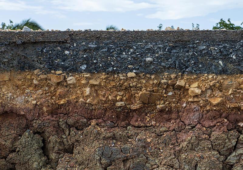 Cross-section of ground showing layers of asphalt, gravel, and soil