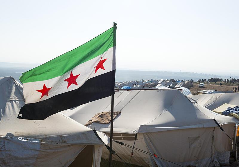 Syrian flag flying over camp tents