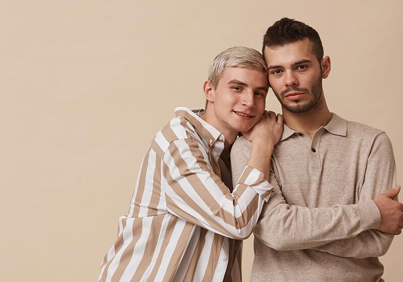 Minimal waist-up portrait of a happy gay couple looking at the camera