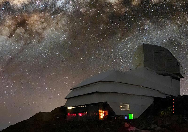 The Vera C. Rubin Observatory illuminated at night under a sky filled with the Milky Way galaxy
