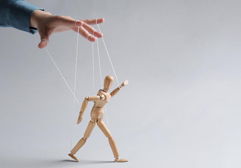 A hand manipulates a wooden puppet with strings