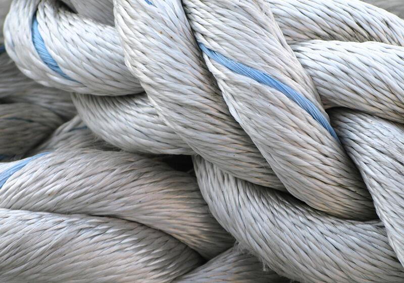 A close-up of a thick, white, coiled rope with a blue stripe