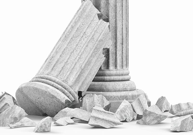 A broken classical column with its top section leaning against the base, surrounded by rubble on a white background