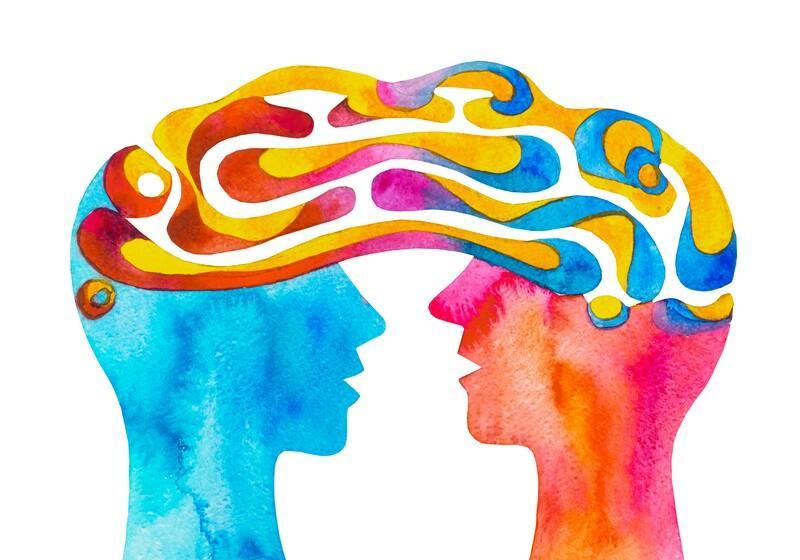 A vibrant watercolour painting showing two human profiles facing each other, their minds connected by a shared, swirling stream of bright yellow, pink, and blue patterns that form the shape of a single brain above them.