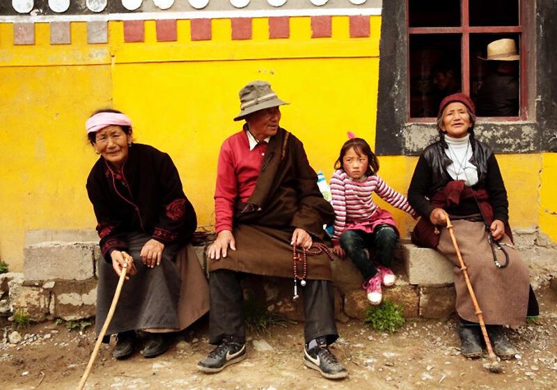Tibetan family sitting against a yellow wall