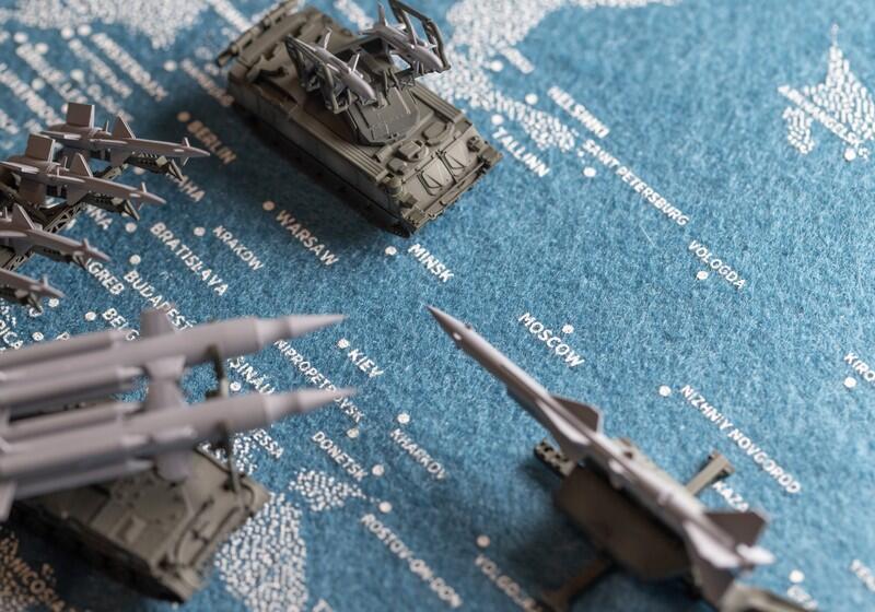 Miniature military vehicle and missile launcher models placed over a blue map of Eastern Europe showing cities like Moscow, Kiev, Warsaw, and Minsk