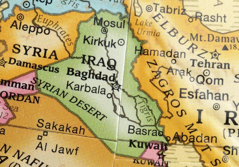 A close-up photograph of a colourful political map focusing on the Middle East, showing labelled countries including Syria, Iraq, Iran, Jordan, and Kuwait, along with major cities like Baghdad, Damascus, and Tehran