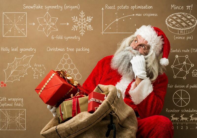 An older man dressed as Santa Claus looking thoughtfully upward while holding a large burlap sack filled with wrapped gifts. He wears a classic red and white suit, a matching hat, white gloves, and has a full white beard