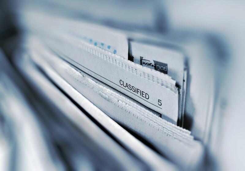 Stack of newspapers from above  with classified pages visible.
