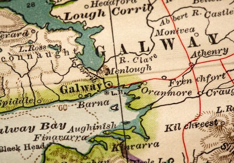 A close-up photograph of an vintage, illustrated paper map focusing on Galway, Ireland, showing coastal features, roads, and surrounding town names like Barna and Oranmore