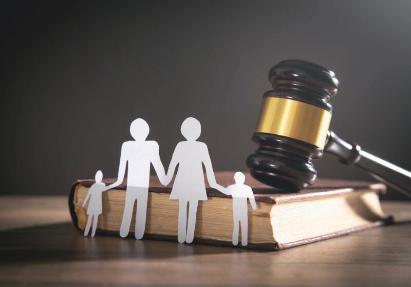 Paper cut outs of woman, man and two children in front of a gavel and book