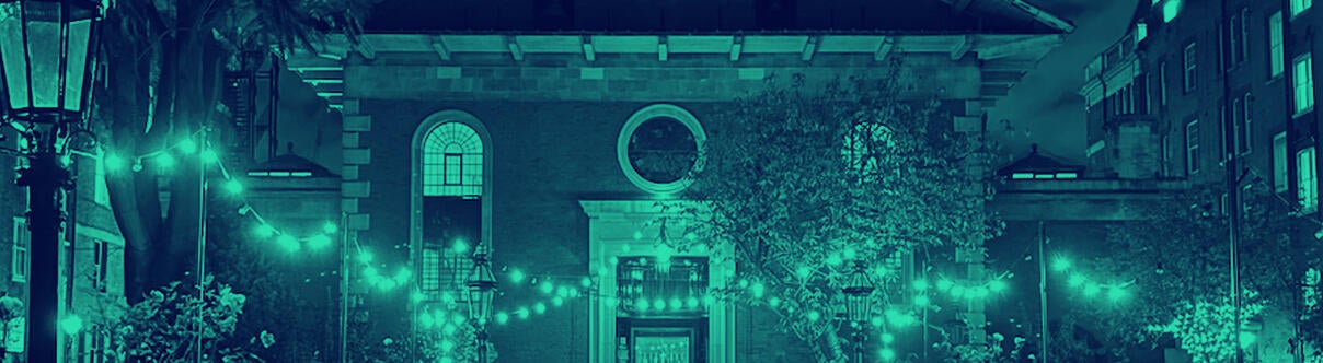 Path towards St Paul's front door lit with strings of bulbs at night
