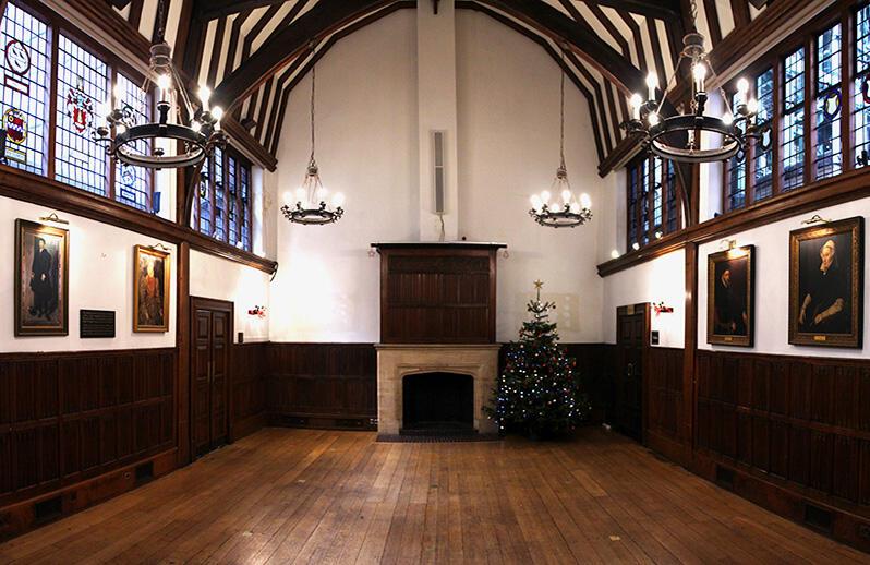 Interior of Barnard's Inn Hall, wooden floor and pannelling, high ceiling, fireplace and chandeliers