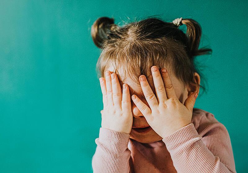 child covering her face with her hands