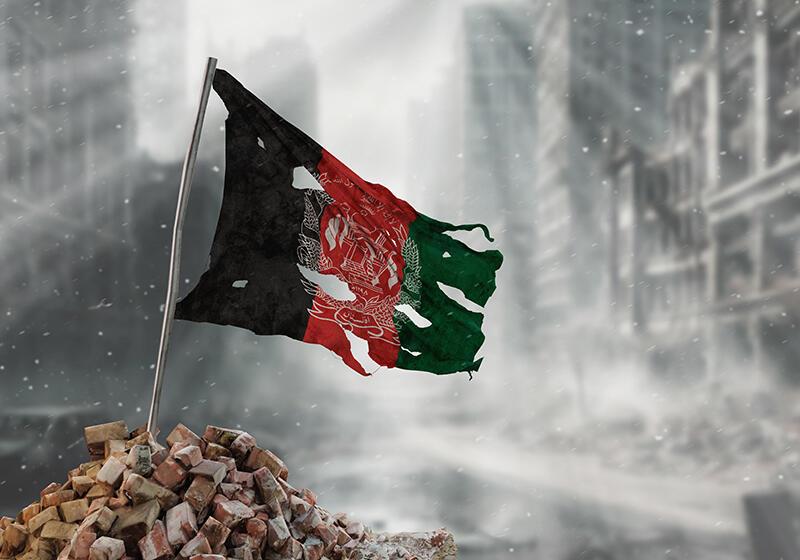 Afghani flag flying above urban rubble