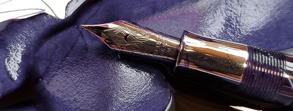 Antique pen lying on ink-stained paper