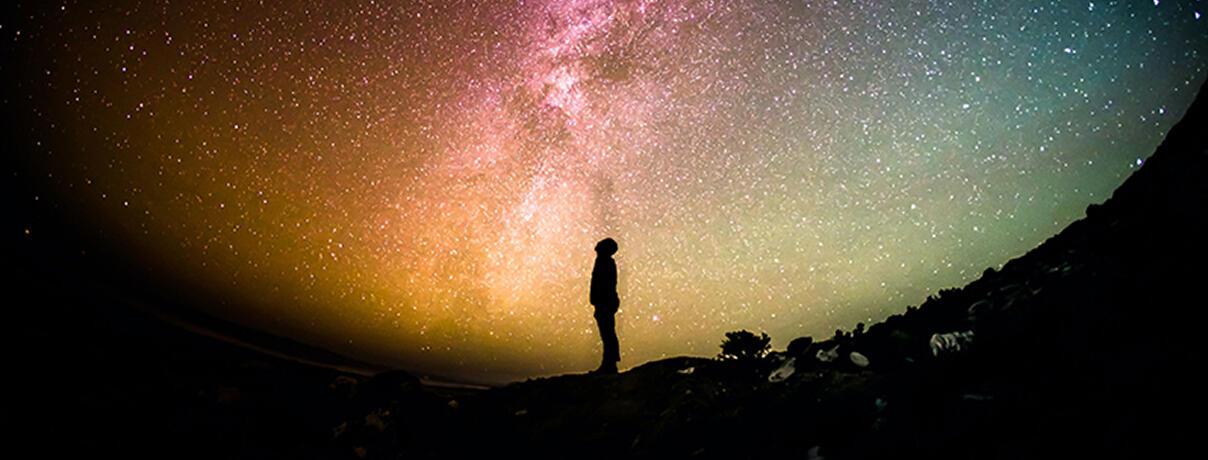 Sillhouette of man staring up at the stars
