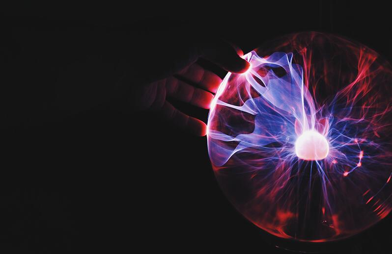 Hand touching plasma globe