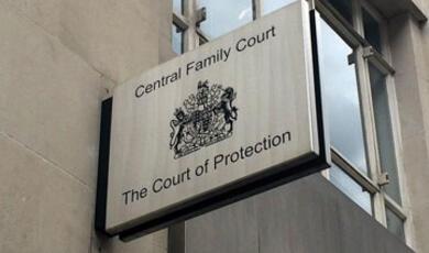 A close-up shot of a sign on a stone building that reads "Central Family Court" at the top and "The Court of Protection" at the bottom, with a coat of arms in the middle