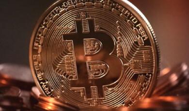 A close-up of a golden Bitcoin coin standing upright amidst other blurred coins