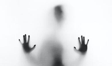 Silhouette of mans hands pressed up against screen