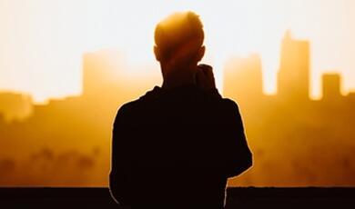 silhouette of young man against city scape and sunshine