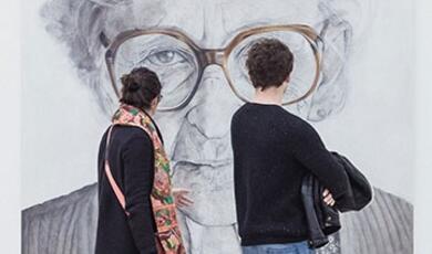 couple looking at large pencil portrait of elderly lady