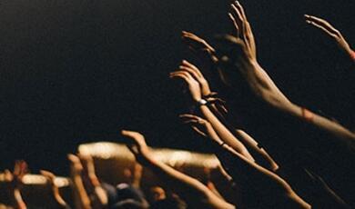 many hands in air at prayer meeting